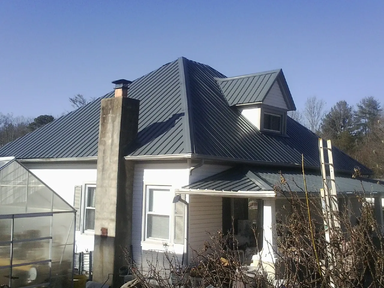 Dark blue standing seam metal roof on a white farmhouse with dormer — Slate & Tile Roof Repair by Roofing Brothers in Rex