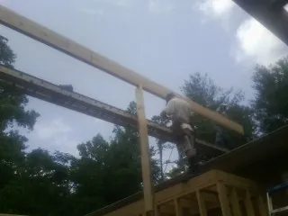 Carpenter setting a ridge beam over a new addition frame — Ice Dam Removal by Roofing Brothers in Rex