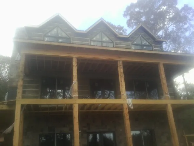 Dormers and porch framing on a large log home under construction — Roof Coating work by our crew in Rex