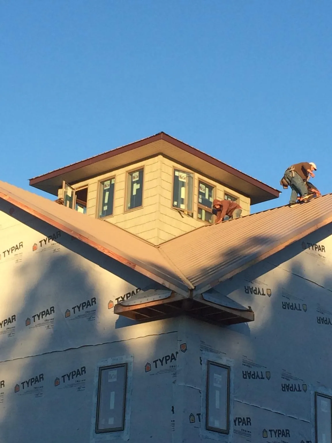 Roofers working around a rooftop cupola on a new metal roof at sunset — Roof Waterproofing in Rex by Roofing Brothers